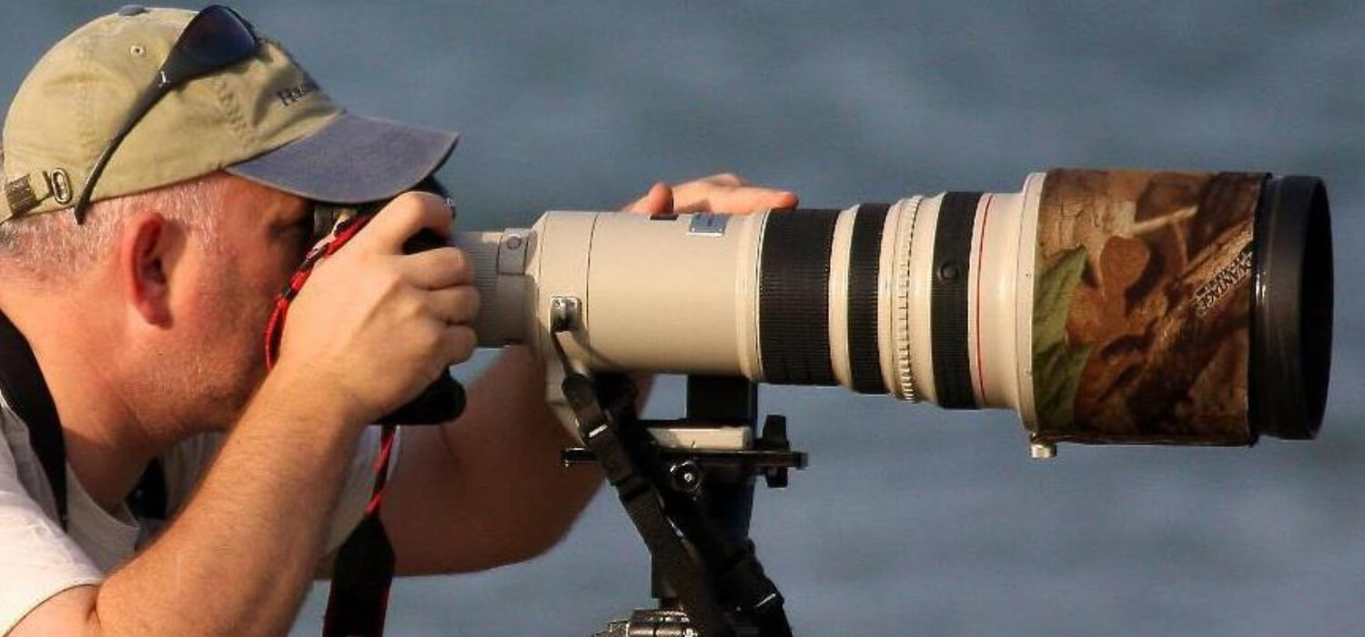 Stuart Elson die-view close up looking through his camera with a very long lens