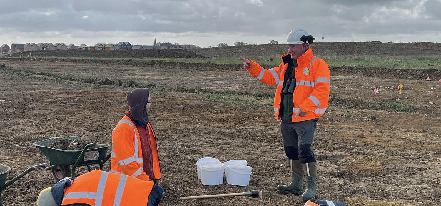 three people in a field with buckets and tools digging for archeological artifacts